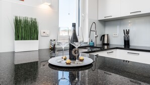 A modern kitchen with a granite countertop, a bottle of champagne, two wine glasses, and a decorative plate with chocolates. - Apartment Birgir in Sukošan (Sukošan)