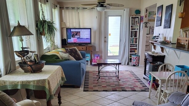 A living room with a sofa, a chair, a television, a ceiling fan, and a bookshelf.