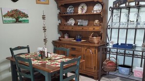 A dining area with a wooden table and chairs, a clock on the wall, and a china cabinet with dishes.