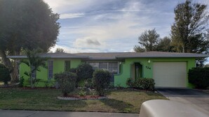 A green house with a garage, a driveway, and a mailbox.