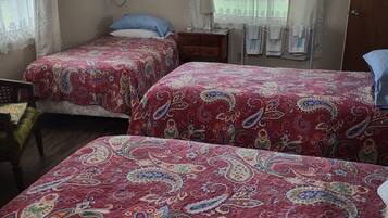 A bedroom with two beds, a ceiling fan, an air conditioning unit, and a window with curtains.