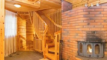 Un interior de madera con chimenea, una escalera y un suelo de baldosas.