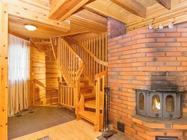 A wooden interior with a fireplace, a staircase, and a tiled floor.