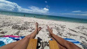 Une scène de plage avec un ciel dégagé, une mer calme et une plage de sable.