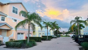 Un quartier résidentiel avec des immeubles à plusieurs étages, des palmiers et des voitures garées.