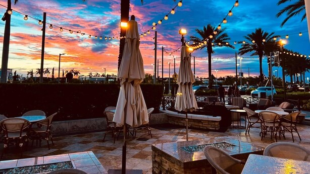 Un espace extérieur aménagé avec des tables, des chaises, des guirlandes lumineuses et des parasols.