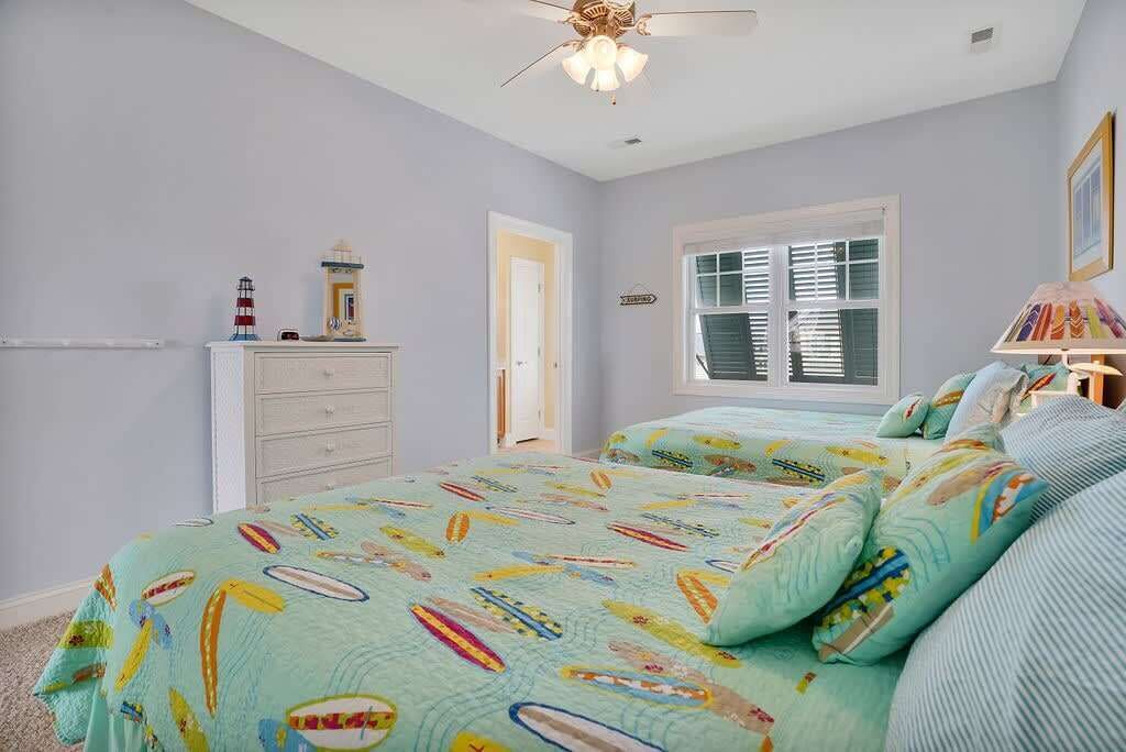A bedroom with a bed, a dresser, a window with blinds, and a ceiling fan.