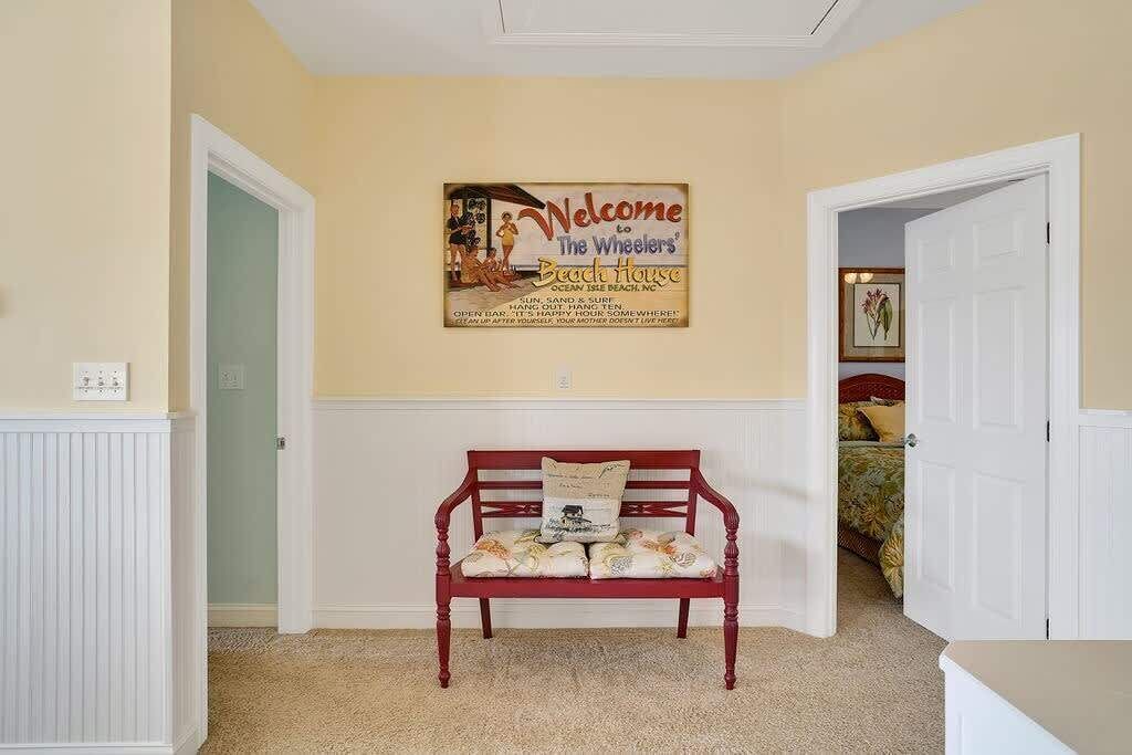 Une pièce avec un banc rouge, un panneau mural et une porte qui donne sur une autre pièce.
