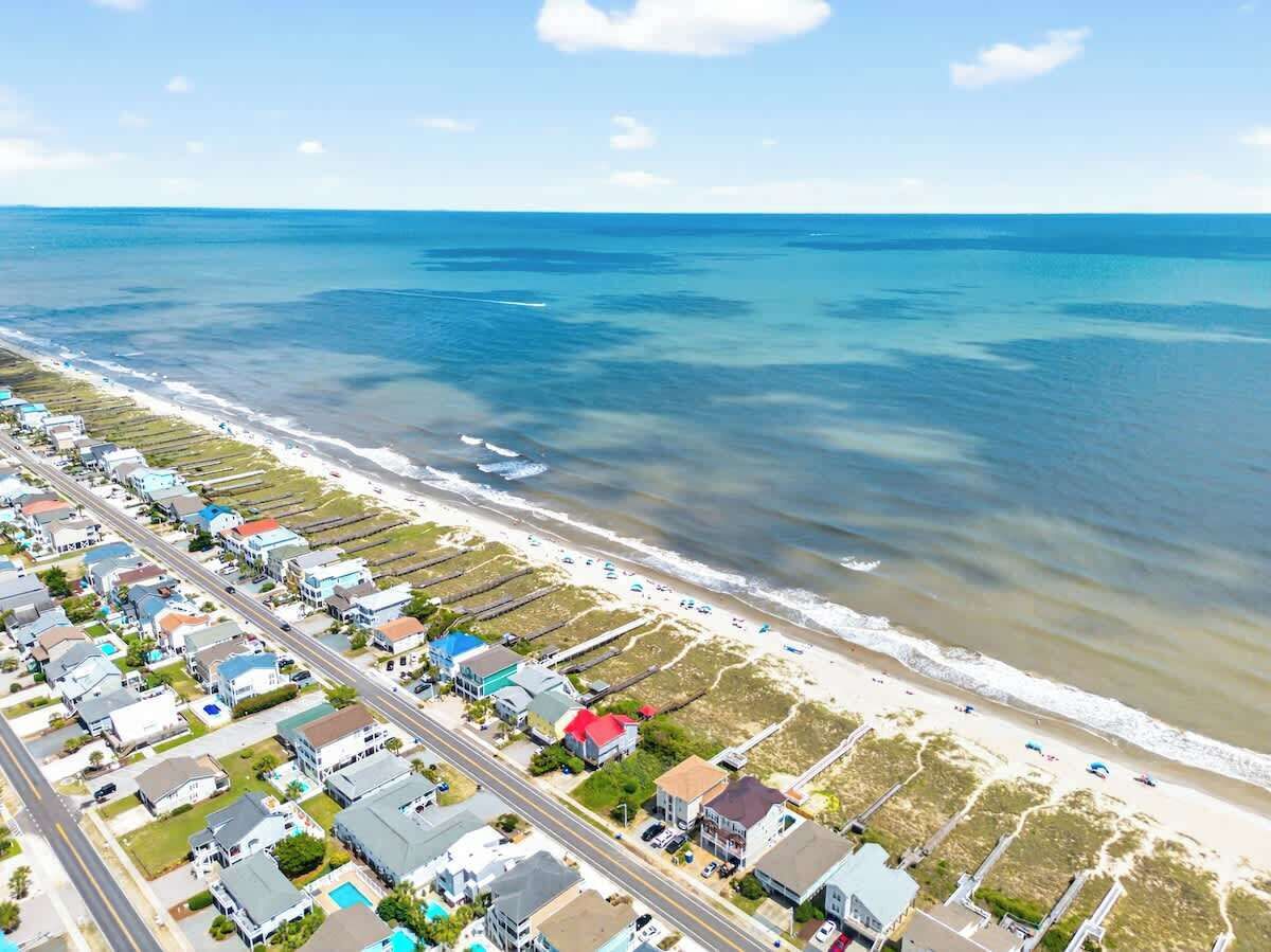 A coastal residential area with houses, a beach, and a road.