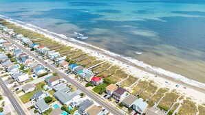 A coastal residential area with houses, a beach, and a road. - Doin` Time by Brunswick Vacation Rentals: 5BR Ocean View Home w/ Dock & Elevator (Ocean Isle Beach)