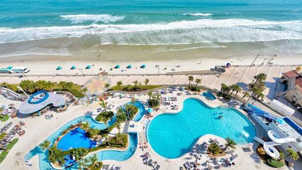 A resort with a large pool, beach, and ocean view.