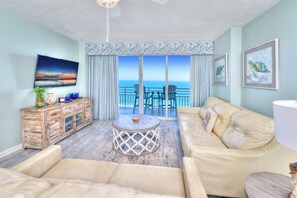 Relax in this stylish living room with a sofa, coffee table, and TV, plus a balcony offering a view of the ocean.