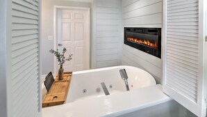 A modern bathroom with a freestanding bathtub, a built-in fireplace, and a wooden vanity.