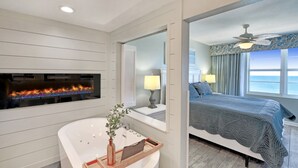 A modern bathroom with a freestanding bathtub, a fireplace, and a large mirror.