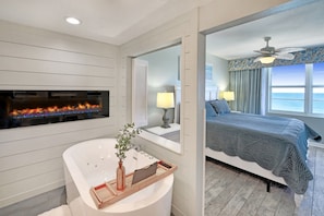 Une salle de bain moderne avec une baignoire sur pieds, une cheminée et un grand miroir.