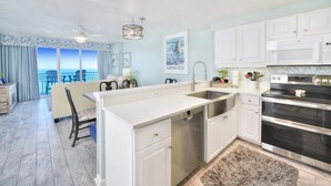 A modern kitchen with white cabinets, stainless steel appliances, and a large island with a sink.