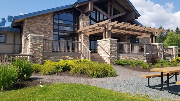 A modern house with a stone facade, large windows, and a covered patio area.