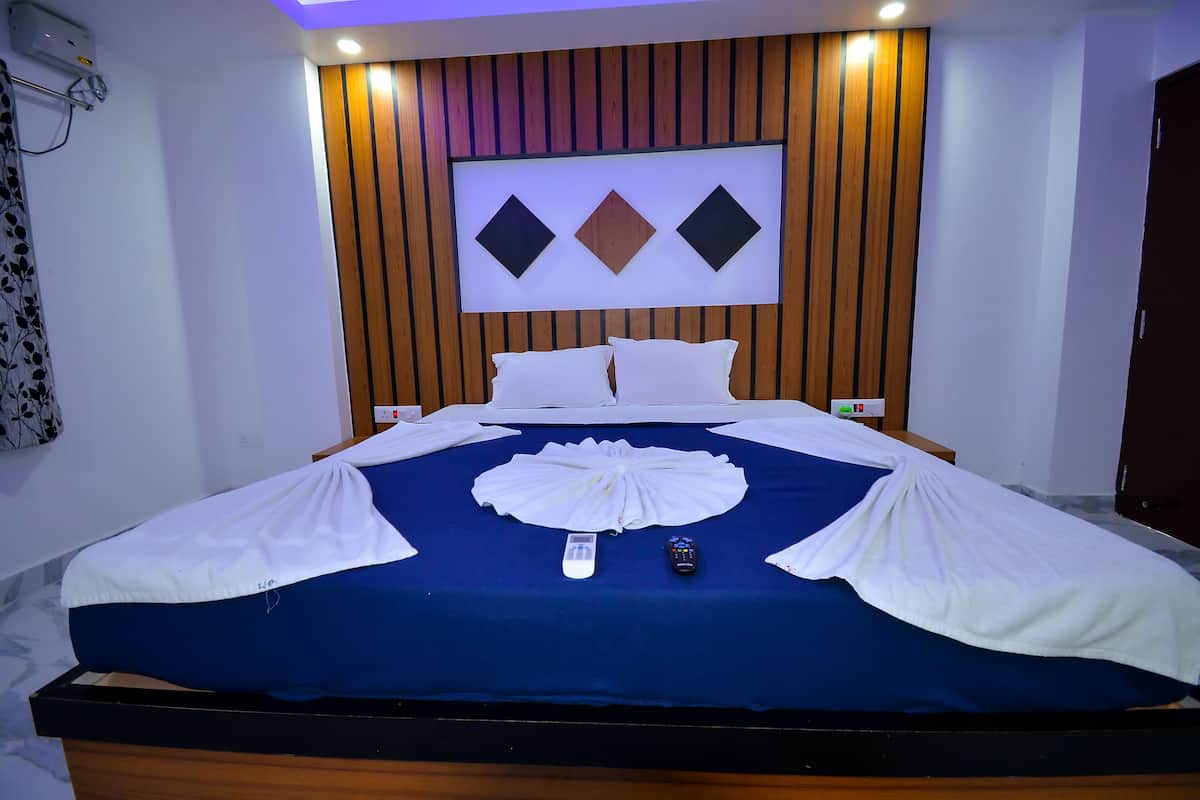 A neatly made bed with a blue and white bedspread, a remote control, and a smartphone on the bed.