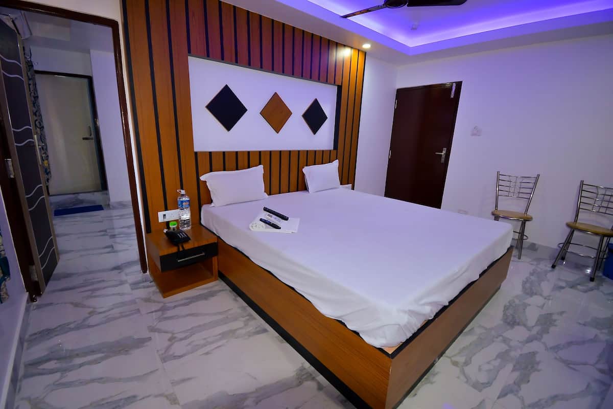 A modern bedroom with a large bed, a nightstand, a wall-mounted TV, and a door.