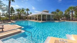 En swimmingpool med liggestole og en pavillon.