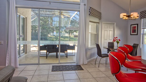A hotel lobby with a glass door leading to an outdoor seating area, a reception desk, and red chairs.