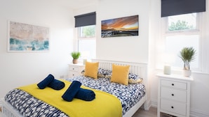 Une chambre à coucher avec un lit, deux tables de chevet, une fenêtre donnant sur un paysage agréable et un luminaire au plafond.