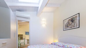 Ein Schlafzimmer mit einem Bett, einem Gemälde und einem Oberlicht.