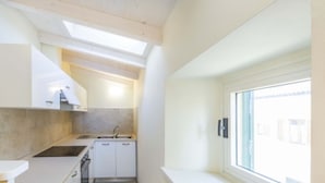 Eine kleine Küche mit Oberlicht, Spüle und Fenster.