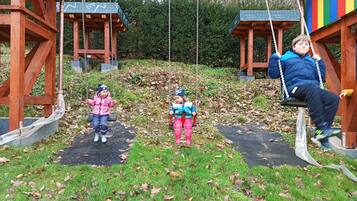 A playground with swings and a wooden structure.