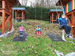 Une aire de jeux avec des balançoires et une structure en bois.