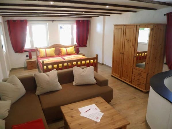 A bedroom with a bed, wooden wardrobe, and a sofa.