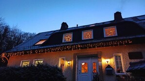 Et hus med skråtag, mange vinduer og lyskæder.