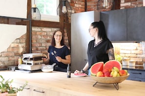 A kitchen with brick walls, a modern refrigerator, and a fruit bowl on the counter. - Doppelzimmer - Pension Waldsauna (Arnsberg)