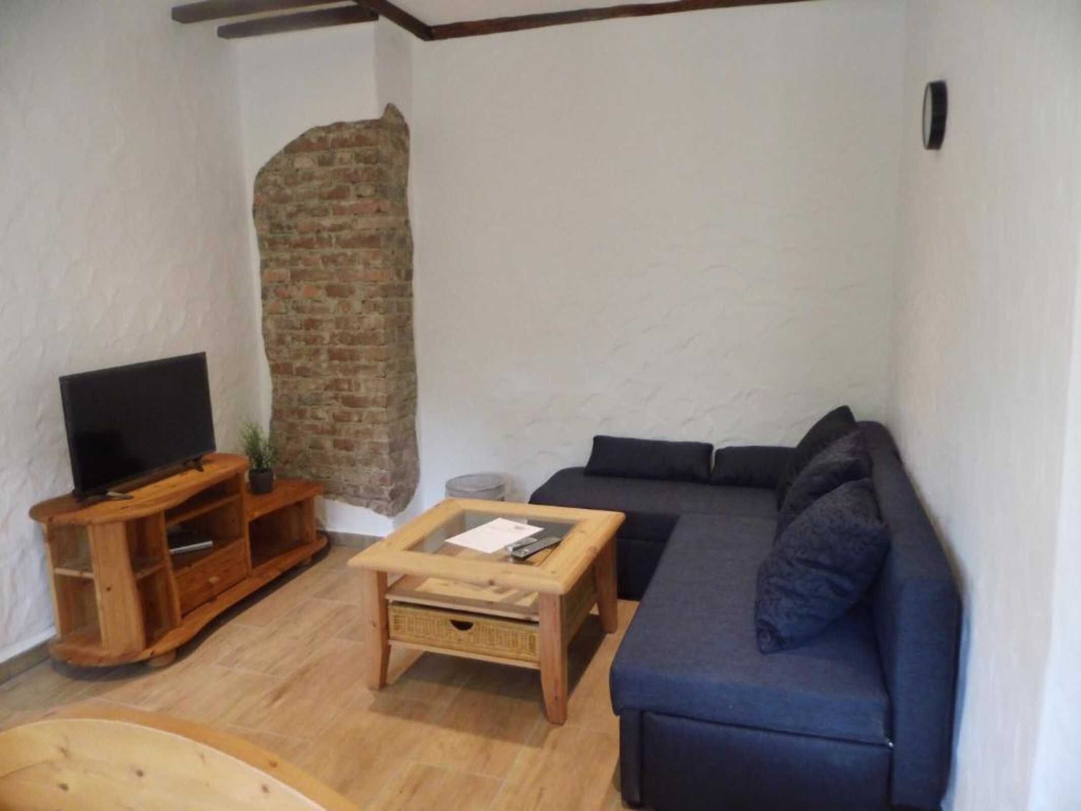 Ein Wohnzimmer mit Fernseher, einer Couch, einem Couchtisch und einer Ziegelwand.