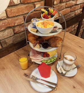 Ein Frühstücksbrett mit Eiern, Früchten, Croissants und einem Glas Orangensaft.