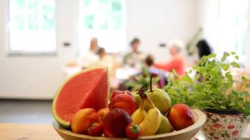 Eine Schale Obst auf einem Tisch, daneben ein Blumentopf.