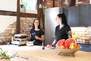 A kitchen with brick walls, a stainless steel refrigerator, and a wooden countertop.