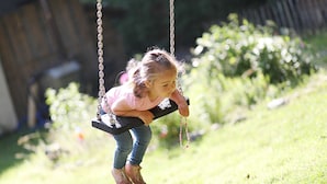 Un niño en un columpio en un espacio al aire libre con césped.