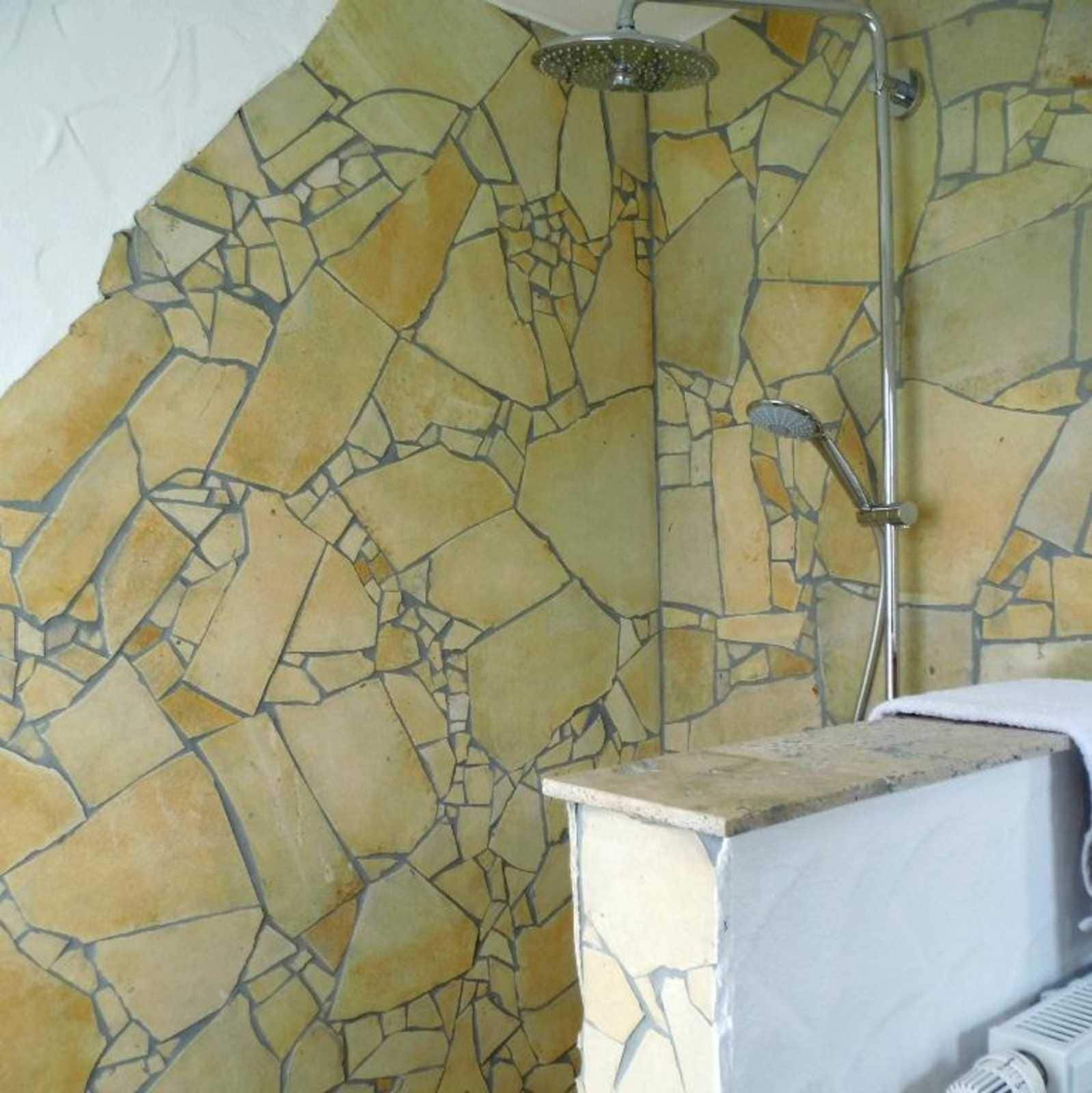 Ein Badezimmer mit Mosaikfliesen, einer Dusche und einem Waschbecken.