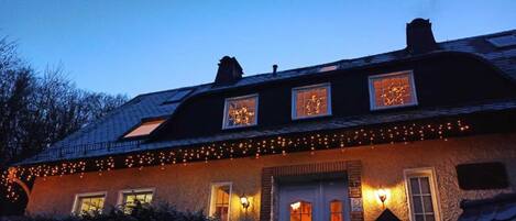 A house with a sloped roof, multiple windows, and string lights.