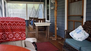 A porch with a swing chair, a table, and a wicker sofa.