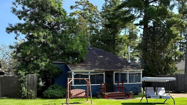 A house with a covered porch, a swing set, and a lawn chair.