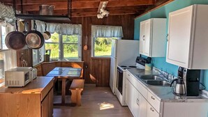 Una cocina rústica con paredes de madera, una mesa de madera y armarios blancos.