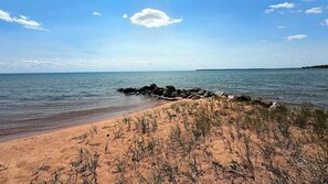 A beach with clear skies, calm water, and a rocky outcrop in the foreground. - 400 Feet Sugar Sand Beach - Barge Bay (La Pointe)