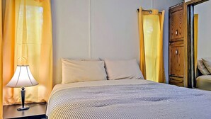 A hotel room with a bed, a nightstand with a lamp, curtains, and a wooden wardrobe.