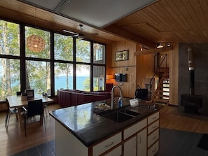A modern kitchen with a large island, wooden walls, and a view of the outdoors.