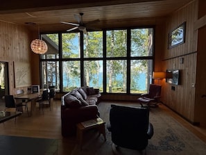 A spacious living area with a large window, a ceiling fan, and a fireplace.