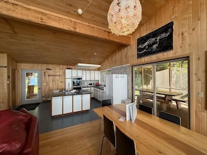 A wooden interior with a kitchen, dining area, and a large window. - Feeling Superior - Cliffside Home with Amazing Lake Views (La Pointe)