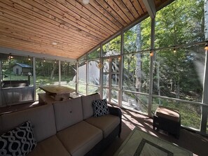 A spacious room with a wooden ceiling, large windows, a sofa, and a table.