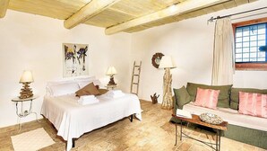 A bedroom with a bed, a green sofa, and a wooden floor.